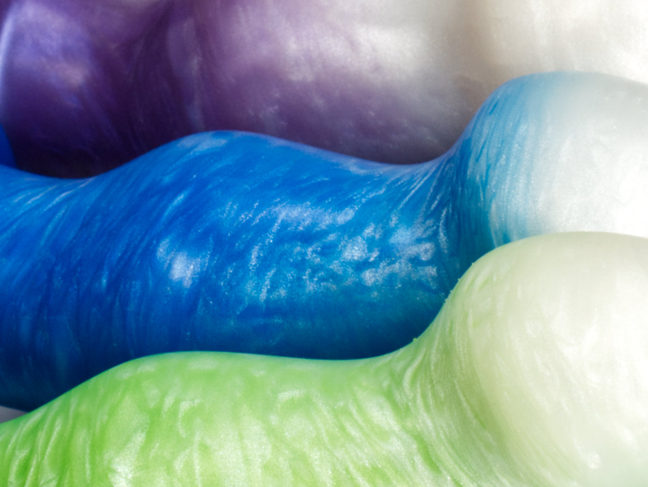 Closeup of several Ally dildos showing their wavy front sides.