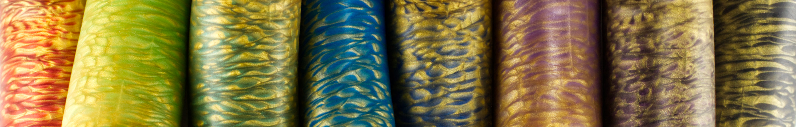 Top view of a row of Sidekick dildos poured in various colors marbled with gold.